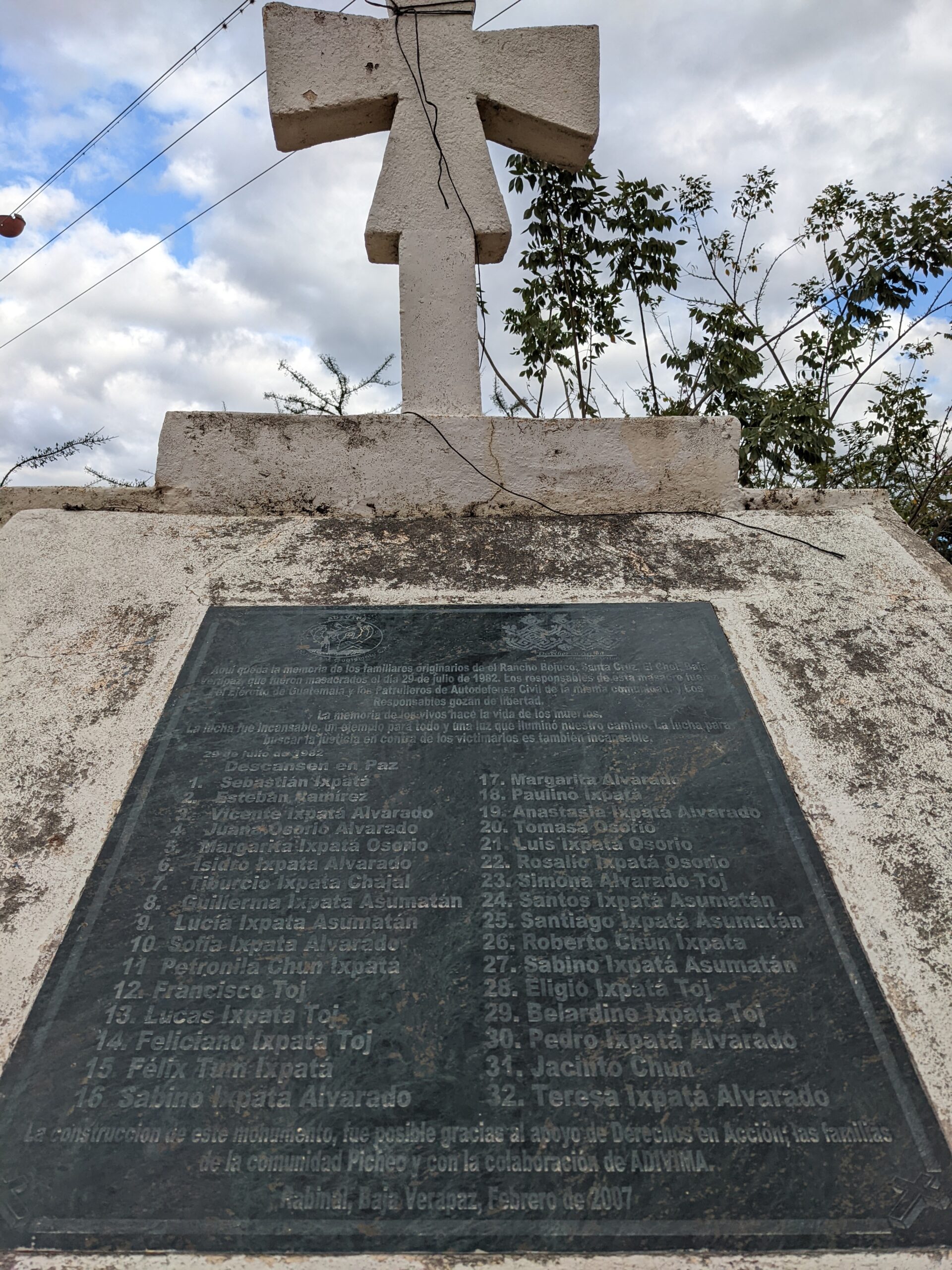 Black monument with cross above it listing the names of Rancho Bejuco massacre victims.